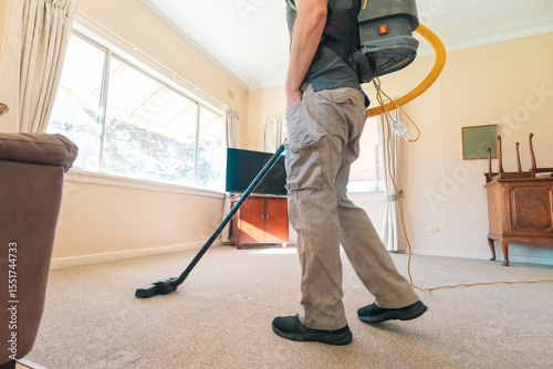 Professional man vacuuming carpet in home in preparation for steam cleaning