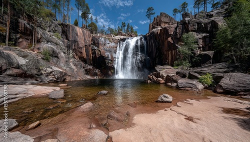 Breathtaking waterfall situated amidst dense woodland and rocky landscape photo