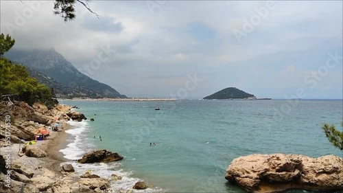 Panorama of the gulf of the Mediterranean Sea with blue water with waves, with a shore with green vegetation, in summer