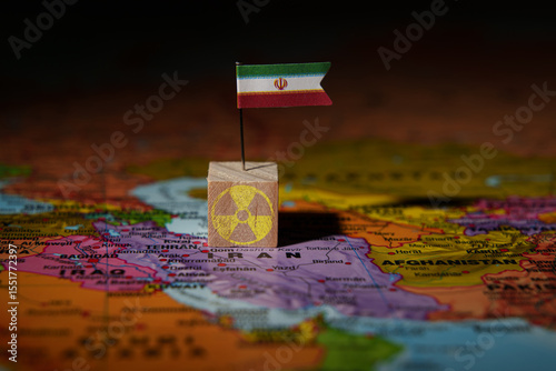 Iran flag pin on map with nuclear symbol block, representing nuclear issue or global tension.