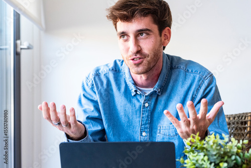 Confident young man sitting at desk with laptop, smiling and speaking directly to the camera. Friendly and professional tone, suitable for tutorials, product reviews, software demos or online presenta