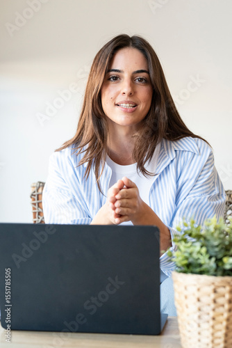 Confident young woman speaking to the camera while sitting at a desk with her laptop. Friendly and professional attitude, ideal for software demos, product reviews, tutorials, or remote presentations
