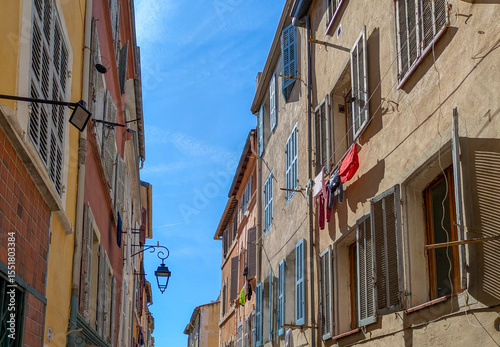 Colorful facades and laundry drying in Le Panier, Marseille, Marseilles, France. Authentic Mediterranean street scene, blue sky, summer atmosphere photo