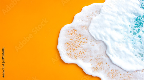 White sea foam waves gently spread over a bright orange sandy beach, creating a vibrant and striking contrast.