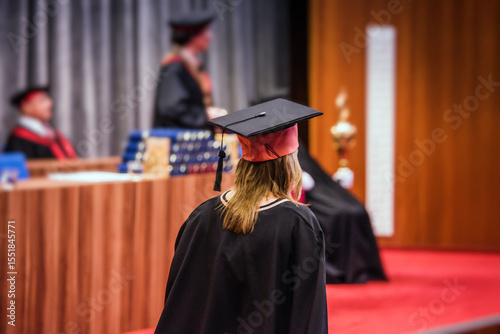 Bilde på lerret Graduation ceremony scene: back view of a female graduate walking on stage to receive her diploma