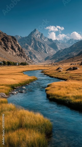 Majestic mountains and serene river flow through golden grasslands under a clear blue sky in the highlands