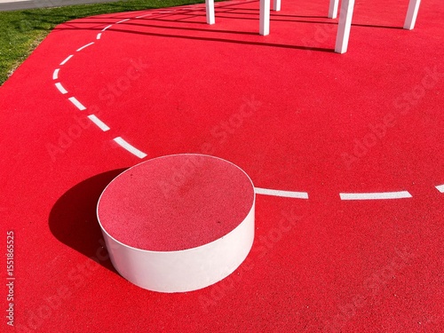 A station on a red fitness trail. The red floor with white markings is elastic.