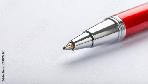 Close up of red and silver pen tip on textured white paper with clean space on left for writing or drawing photo