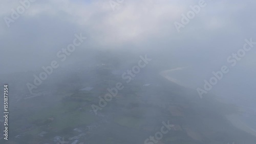 Fog and clouds over green fields and coastline on small island