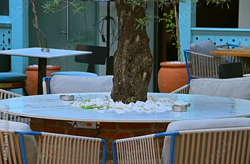 Table with a tree in the middle on the open veranda of a restaurant