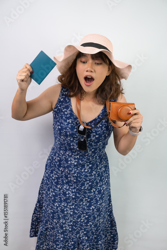 Beautiful young asian woman wearing blue summer dress and beach straw hat is holding indonesian passport, isolated over white background.