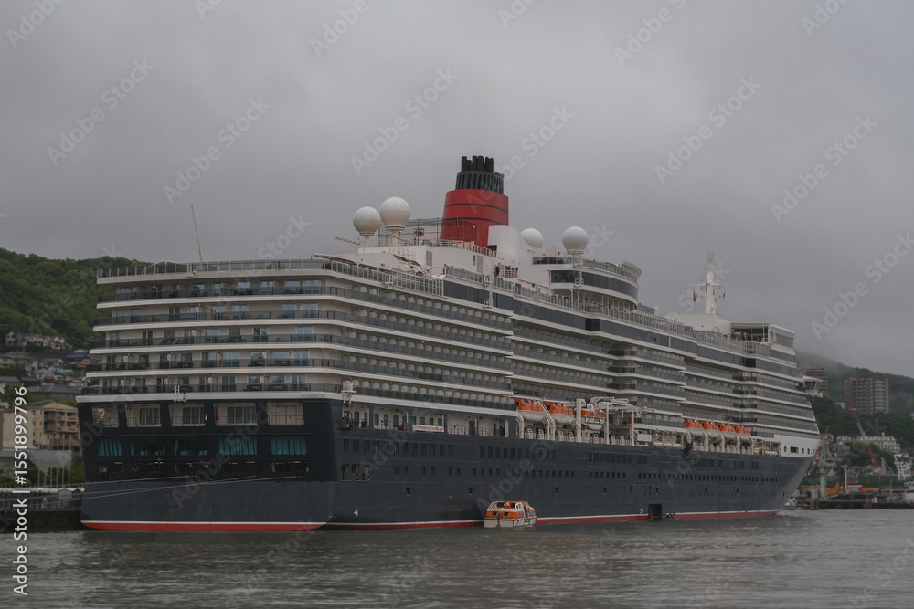 Obraz premium Classic ocean liner cruiseship cruise ship Elizabeth in port of Nagasaki, Japan with skyscraper downtown city skyline during summer Honshu circumnavigation cruising for cherry blossom bloom