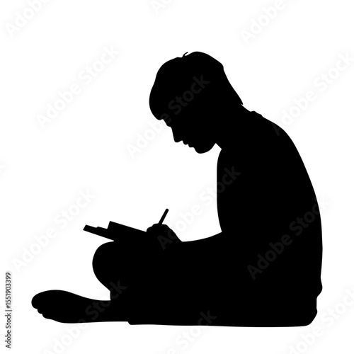 Boy silhouette writing in notebook while sitting on the floor  