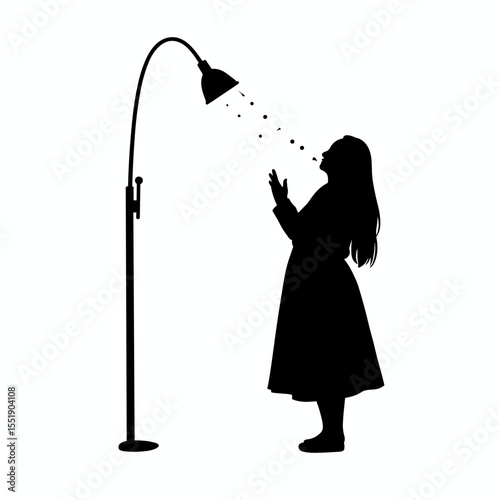 Silhouette of a girl enjoying light from a lamp indoors  