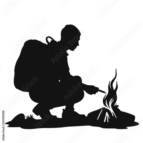 Silhouette of a man crouching and making a fire outdoors  