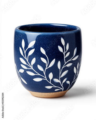 A dark blue ceramic cup with white leaf designs on a white background in a studio setting view