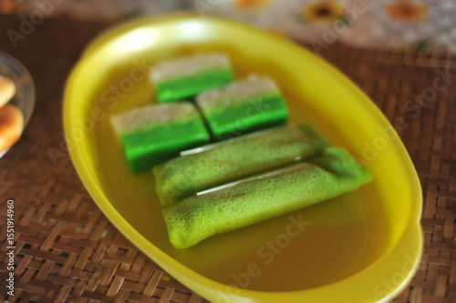 Kuih Dadar (green-coloured folded omelette or pancake made of rice flour) and  Kuih Talam Pandan (Pandan Sticky Ricke Cake) on a plastic tray.