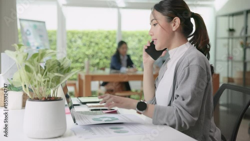 Real estate agent female asia people go green net zero waste control ESG audit office desk. Young adult woman asian SDGs auditor busy happy work using mobile phone call advice stock trader specialist.