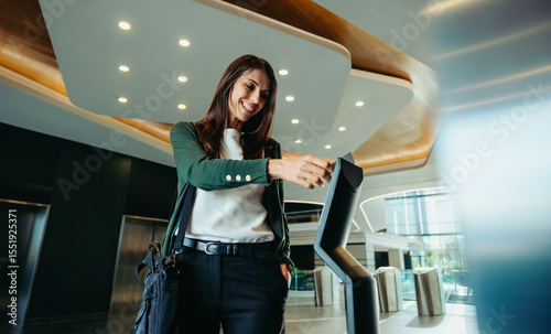 Smiling businesswoman swiping keycard at entrance checkpoint