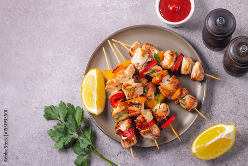 Delicious grilled chicken skewers with capsicum, lemon, salad and ketchup on a plate over the table. Chicken kebab. Healthy food concept.