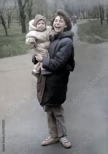 Vintage portrait of mother and daughter on a walk. Happy laughing mother holds her baby in her arms. Retro photo 1995.