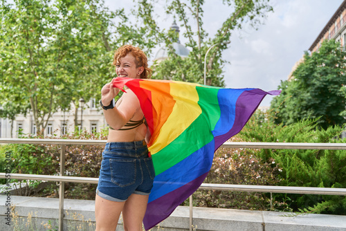Young woman showing a rainbow flag at gay pride parade photo