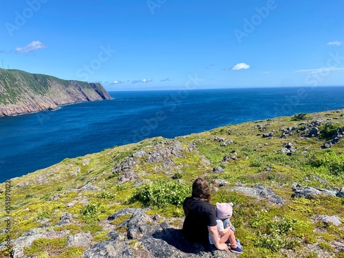A mother and daughter enjoying the beautiful view of Logy Bay, outside St. John's newfoundland, on a beauty sunny summer day with the ocean sparking in the distance