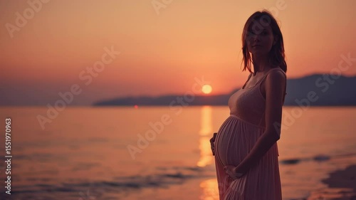 Pregnant woman gently holding her belly while standing by the sea during a peaceful sunset, reflecting a calm and emotional moment.
