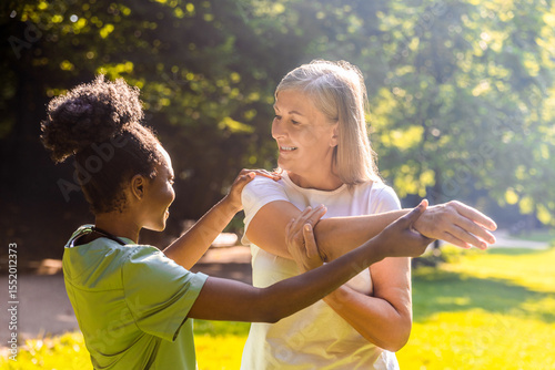 Senior and caregiver engaging in rehab exercise in park