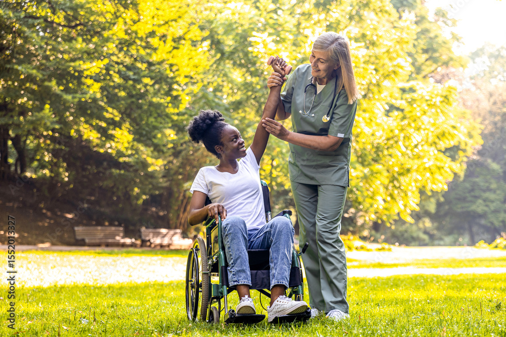 African American woman in wheelchair with caregiver during park rehab African American woman in wheelchair with caregiver during park rehab