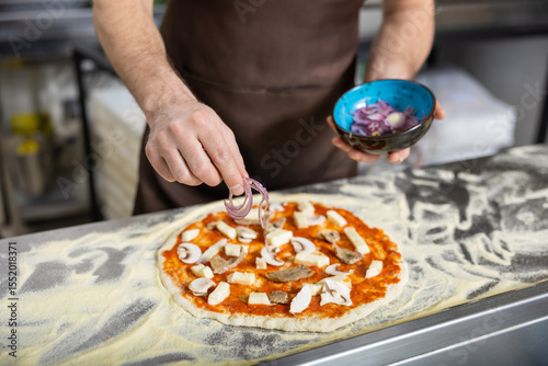 Φωτογραφία Close up picture of cookers hands putting topping o the pizza