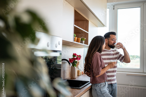Couple drinking milk in modern kitchen, embracing domesticity