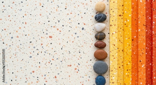 Colorful stones are neatly stacked near bright orange texture bars on speckled surface