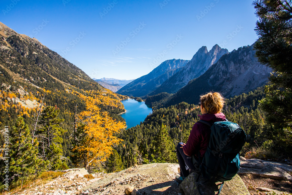 Fototapeta premium Young hiker woman in autumn in Aiguestortes and Sant Maurici National Park, Spain