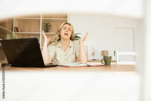 A young woman expresses frustration while working from home, reflecting the challenges of remote work and stress management.