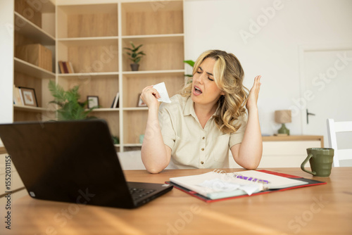 A woman joyfully sings while working at her desk, surrounded by personal items and a laptop, expressing happiness and creativity.