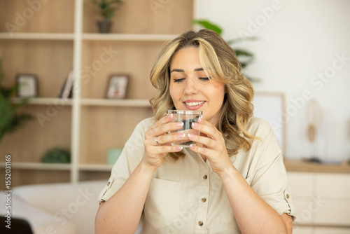 A woman savors her drink, highlighting relaxation and comfort in a cozy, well-decorated living space, filled with greenery.