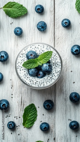 Creamy chia pudding topped with fresh blueberries and mint leaves on a rustic wooden background