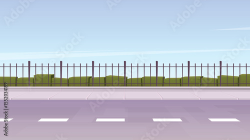 A low-angle view of an empty roadside featuring a fence and a row of green bushes.  The scene is set under a light blue sky, suggesting a calm and peaceful day.