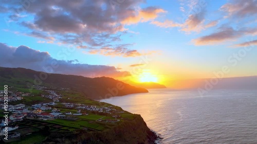 Aerial view of a colourful sunset over the dramatic coastline of São Miguel Island in the Azores, Portugal, with green fields and Atlantic Ocean