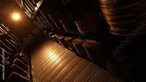 Dark film archive corridor, shelves filled with golden film canisters. A bright light illuminates a classic film reel and old film strip, symbolizing cinematic history and discovery.
