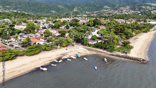 Praia Barra Velha em Ilhabela, São Paulo, com mar calmo e casas à beira-mar. Um destino paradisíaco no litoral norte paulista