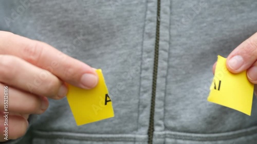 A woman ripping a yellow piece of paper with the abbreviation AI on it.