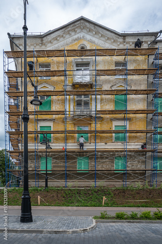 An old building in scaffolding during renovation and painting of the facade.