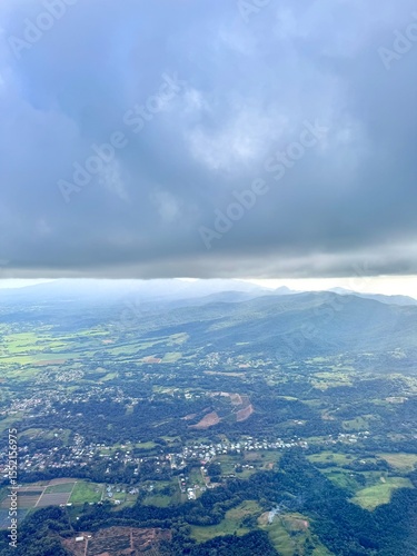 flight over Guadeloupe with a view of the town of Sainte Rose with green mountains in the background
