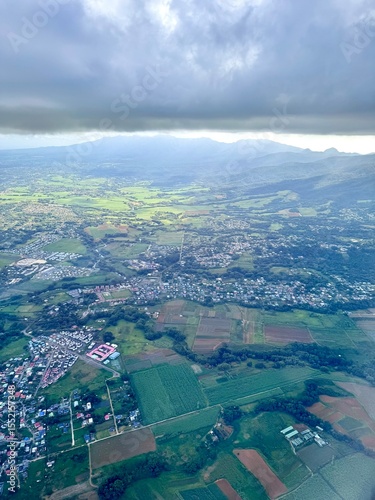 flight over Guadeloupe with a view of the town of Sainte Rose with green mountains in the background
