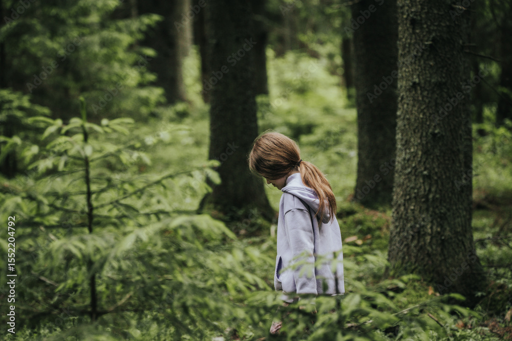 A young girl in a lavender hoodie and pink pants walks through a mossy forest, holding a plastic jar, possibly collecting insects or exploring nature. A young girl in a lavender hoodie and pink pants walks through a mossy forest, holding a plastic jar, possibly collecting insects or exploring nature.