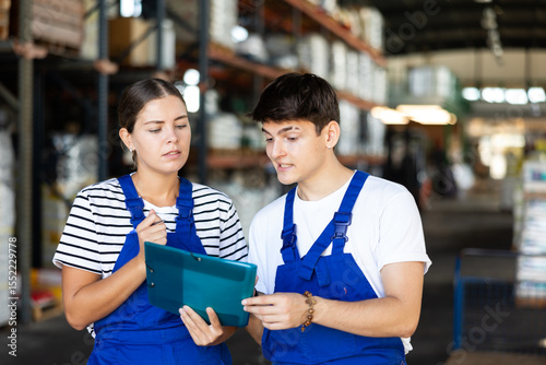 Young girl manager boss checks papers invoices together with guy employee and revise availability and quantity of goods in stock