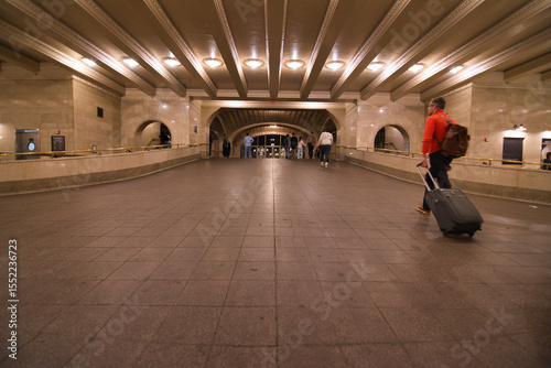 A man in red jumper pulling from his suitcase entering the train station