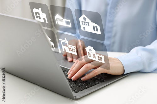 Real estate agent looking for housing via laptop at white table, closeup. Illustrations of different dwellings over device